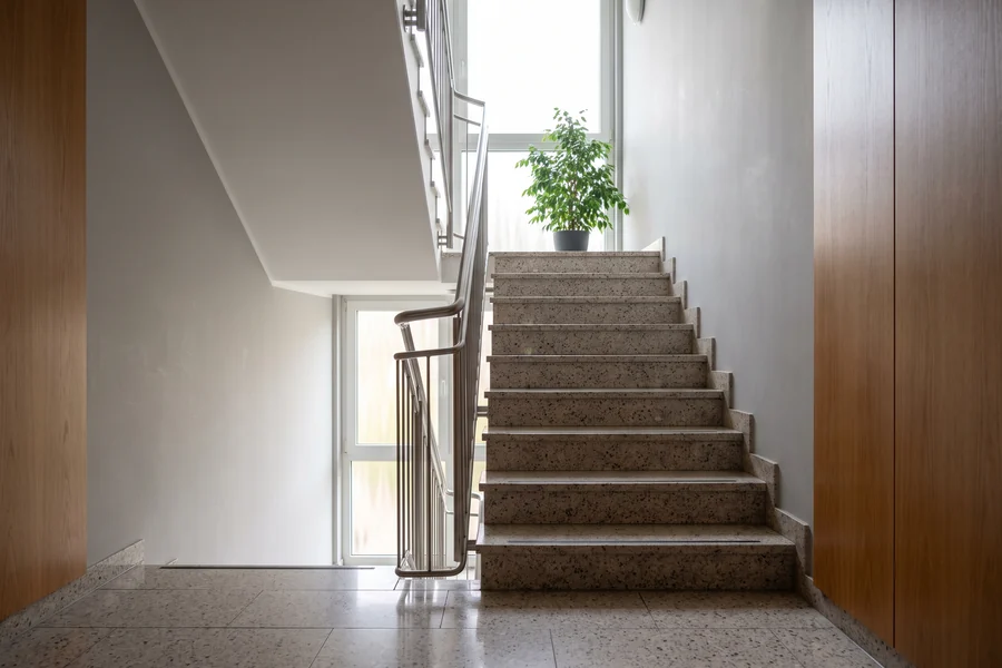 Sauberes Treppenhaus einer Wohnanlage mit Terrazzostufen und Handlauf